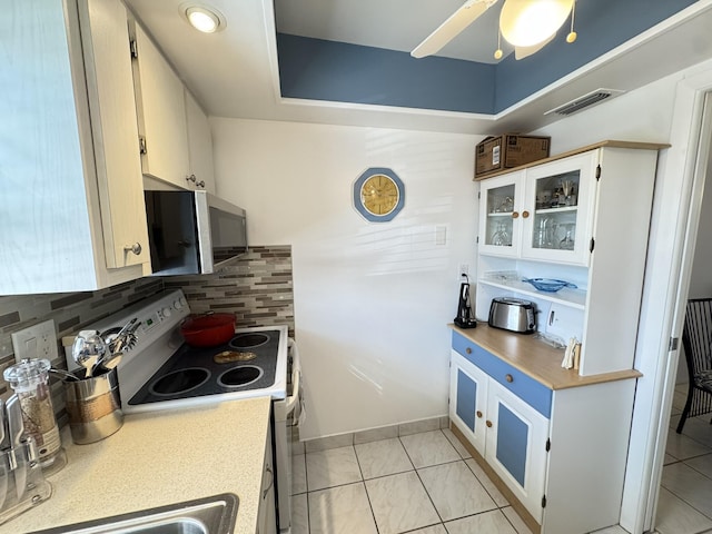 kitchen featuring backsplash, electric range oven, ceiling fan, light tile patterned floors, and white cabinets