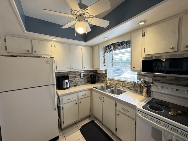 kitchen with white appliances, sink, decorative backsplash, light tile patterned floors, and a tray ceiling