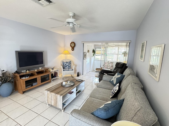 living room featuring ceiling fan, light tile patterned flooring, and a textured ceiling