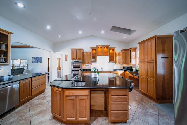 kitchen featuring vaulted ceiling, light tile patterned flooring, an island with sink, and stainless steel appliances