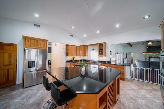 kitchen featuring kitchen peninsula, appliances with stainless steel finishes, a kitchen breakfast bar, vaulted ceiling, and a kitchen island