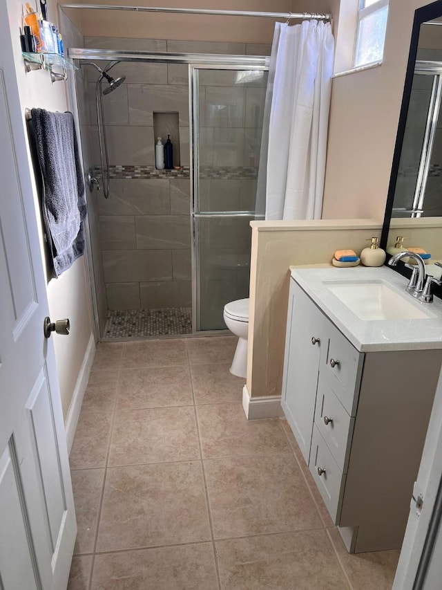 bathroom with tile patterned flooring, vanity, toilet, and an enclosed shower