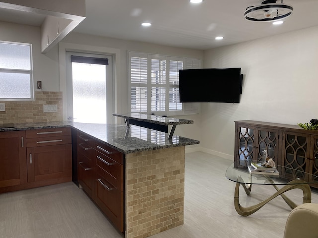 kitchen with tasteful backsplash, dark stone counters, a peninsula, and recessed lighting