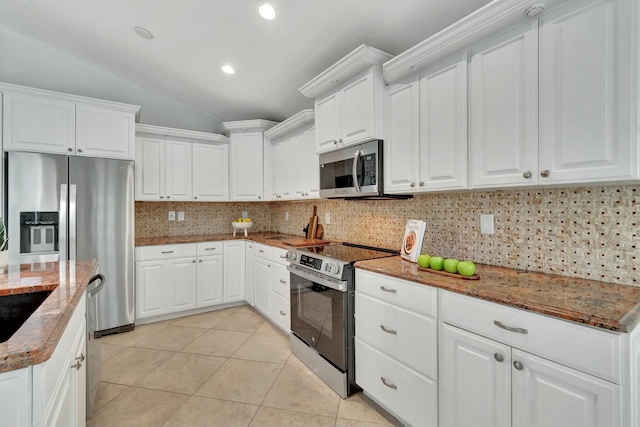 kitchen with white cabinetry, tasteful backsplash, light tile patterned floors, dark stone countertops, and stainless steel appliances