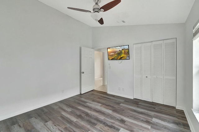 unfurnished bedroom featuring ceiling fan, dark hardwood / wood-style floors, vaulted ceiling, and a closet