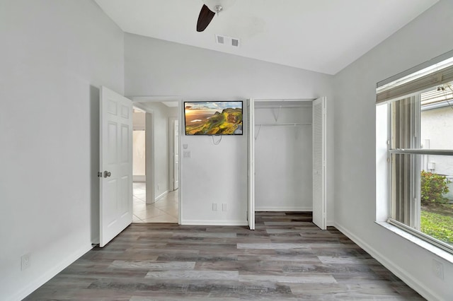 unfurnished bedroom with dark hardwood / wood-style flooring, vaulted ceiling, a closet, and ceiling fan