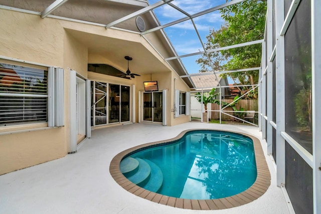 view of swimming pool with ceiling fan, a lanai, and a patio