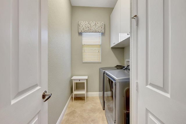 washroom with washing machine and clothes dryer and cabinets