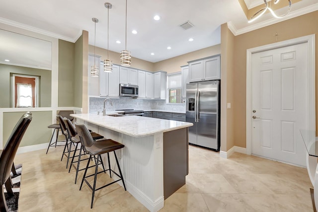 kitchen with pendant lighting, appliances with stainless steel finishes, kitchen peninsula, light stone counters, and a breakfast bar area