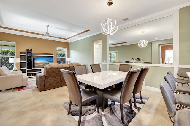 dining area with a raised ceiling, a chandelier, and ornamental molding