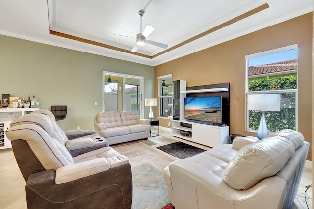 living room with ceiling fan, a wealth of natural light, crown molding, and a raised ceiling