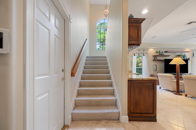 stairs featuring tile patterned flooring and an inviting chandelier