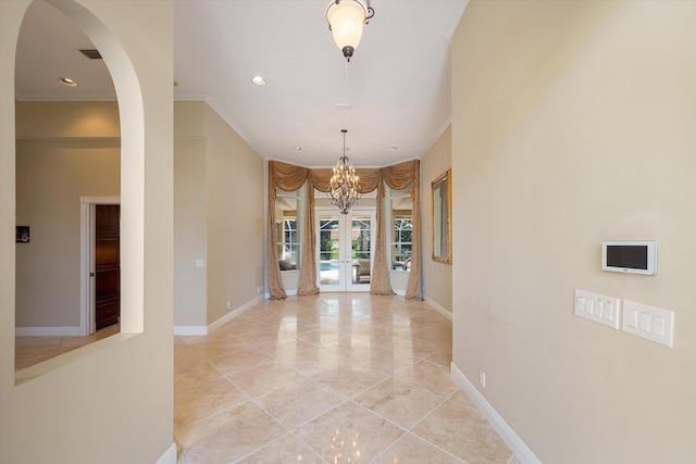 foyer entrance featuring a chandelier, french doors, and crown molding