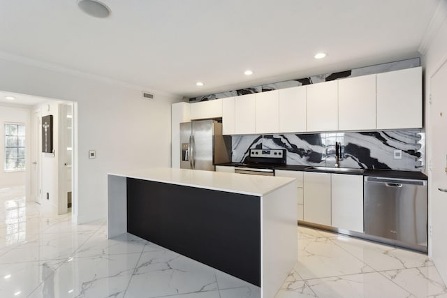 kitchen featuring white cabinetry, a center island, stainless steel appliances, decorative backsplash, and ornamental molding