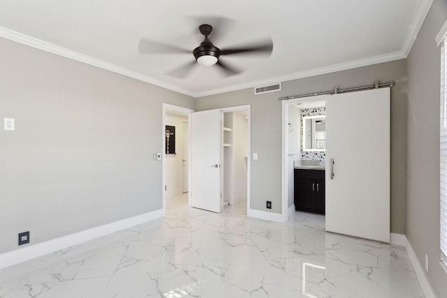 unfurnished bedroom with a spacious closet, ceiling fan, crown molding, ensuite bathroom, and a closet