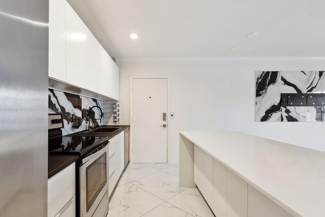 kitchen featuring white cabinetry, sink, stainless steel appliances, backsplash, and ornamental molding