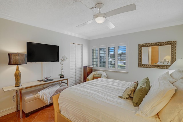 bedroom with ceiling fan, tile patterned flooring, crown molding, a textured ceiling, and a closet