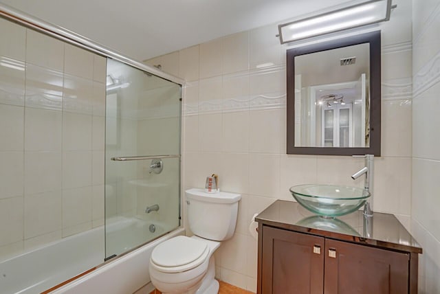 full bathroom with vanity, enclosed tub / shower combo, tile walls, and toilet