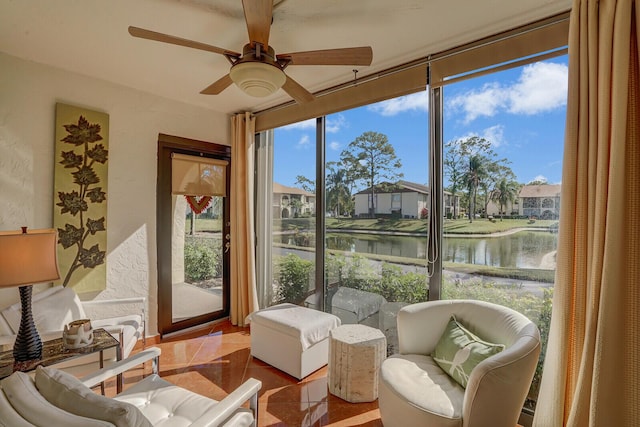 sunroom / solarium with ceiling fan and a water view