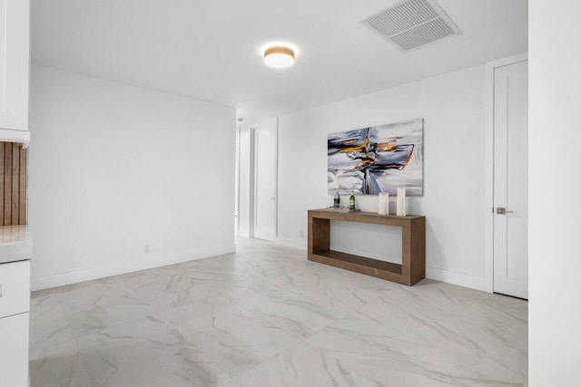 empty room with marble finish floor, visible vents, and baseboards