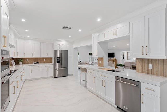 kitchen with a sink, visible vents, marble finish floor, appliances with stainless steel finishes, and decorative backsplash