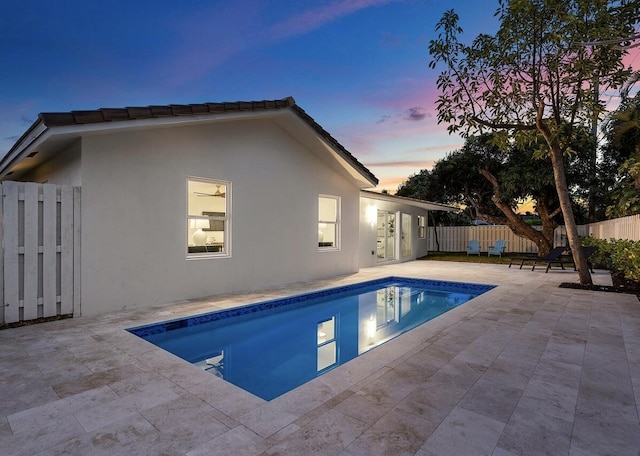 pool at dusk with a patio area, a fenced backyard, and a fenced in pool