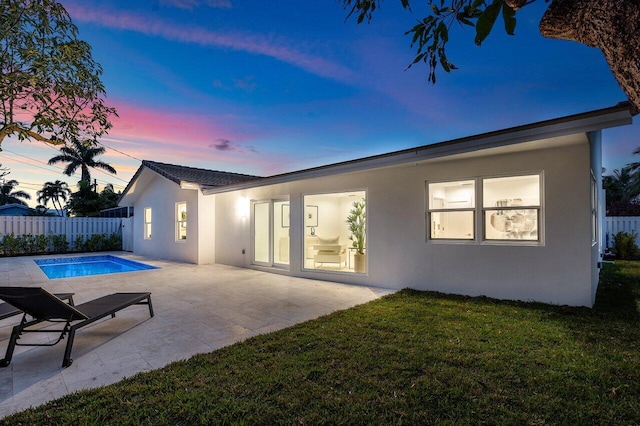 rear view of property with a lawn, fence, a patio, and stucco siding