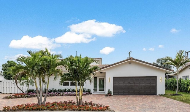 view of front of house featuring a garage, fence, french doors, decorative driveway, and stucco siding