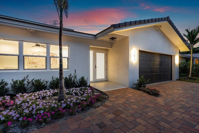 view of front of home with decorative driveway, an attached garage, and stucco siding