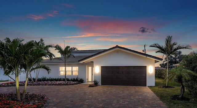 ranch-style home with an attached garage, decorative driveway, and stucco siding