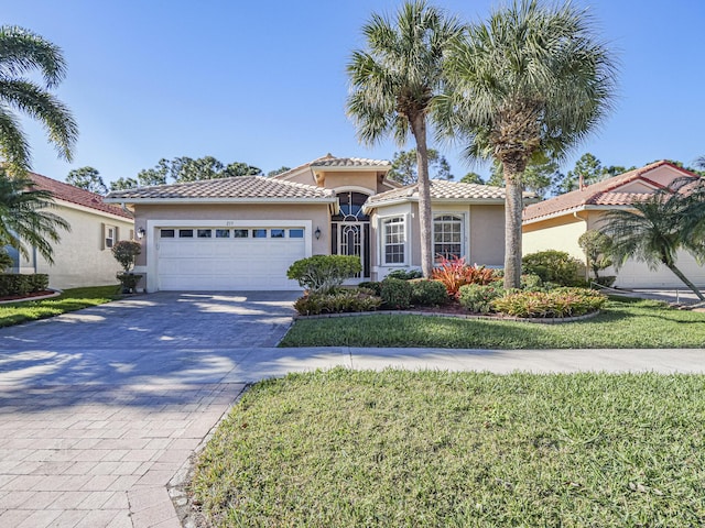 mediterranean / spanish home featuring a front yard and a garage