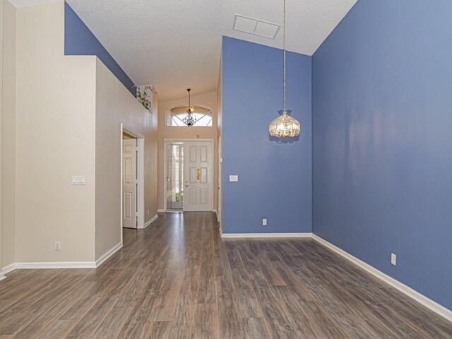 entrance foyer featuring dark hardwood / wood-style flooring, high vaulted ceiling, a chandelier, and a textured ceiling