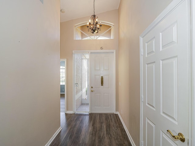 entrance foyer with dark hardwood / wood-style flooring, high vaulted ceiling, and a notable chandelier