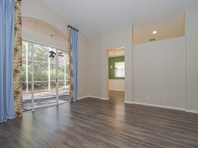 empty room with dark hardwood / wood-style floors, plenty of natural light, and an inviting chandelier