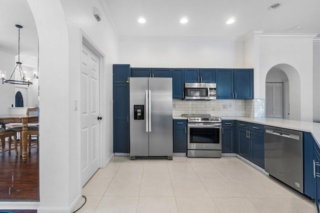 kitchen with decorative backsplash, stainless steel appliances, blue cabinetry, an inviting chandelier, and hanging light fixtures