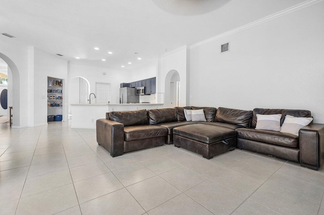 living room with sink, crown molding, and light tile patterned flooring