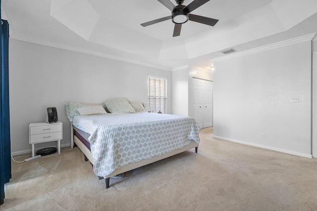 carpeted bedroom featuring a closet, a raised ceiling, ceiling fan, and ornamental molding