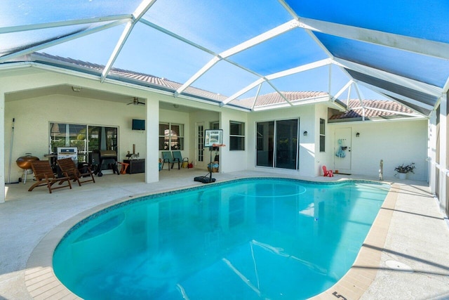 view of swimming pool featuring a patio, glass enclosure, and ceiling fan