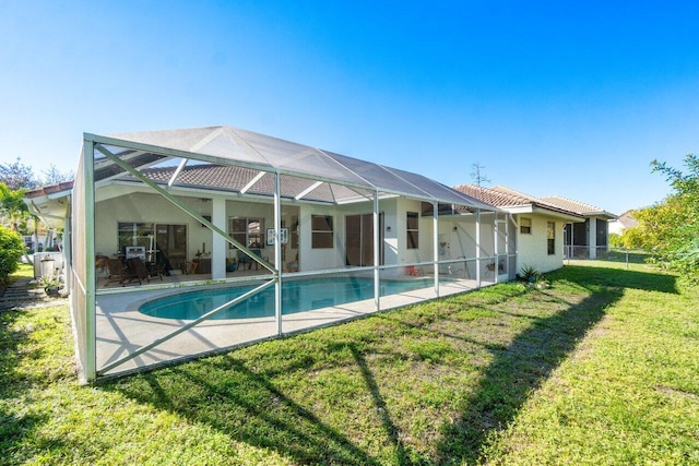 back of house with glass enclosure, a patio area, and a yard