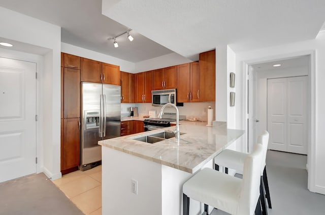 kitchen with light tile patterned floors, a breakfast bar area, appliances with stainless steel finishes, and kitchen peninsula