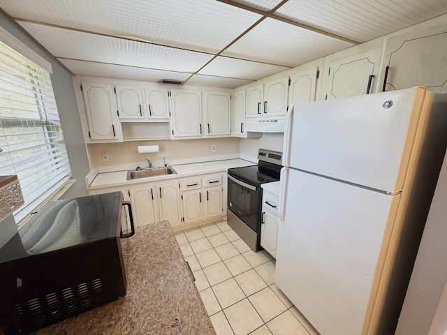 kitchen featuring stainless steel range with electric stovetop, sink, light tile patterned floors, white refrigerator, and white cabinetry