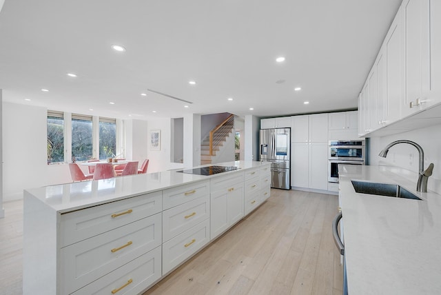 kitchen featuring white cabinetry, sink, light wood-type flooring, and appliances with stainless steel finishes