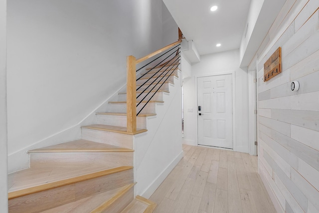 stairs featuring wood walls and wood-type flooring