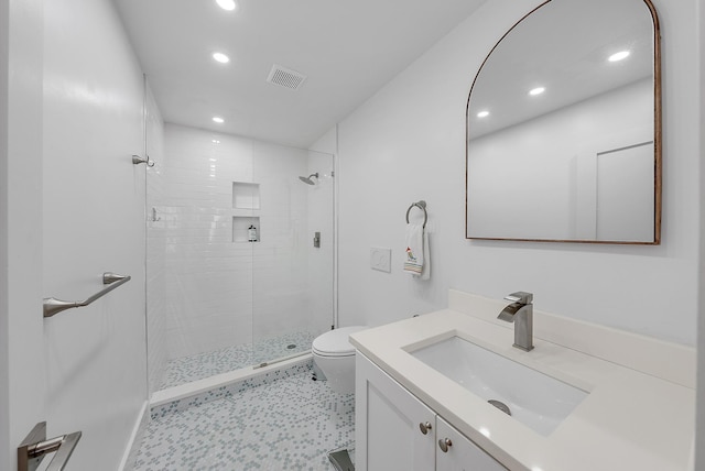 bathroom with vanity, toilet, and a tile shower