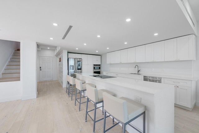 kitchen featuring a kitchen bar, a large island, white cabinets, and stainless steel appliances