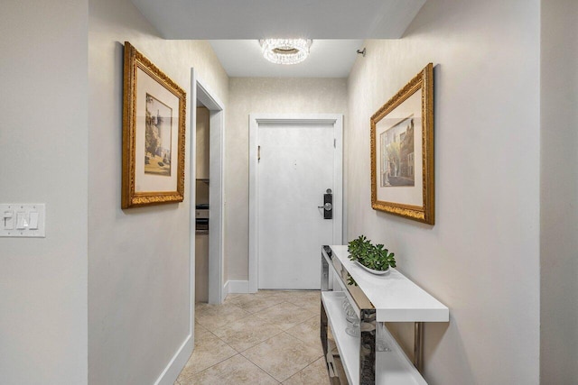 hallway with light tile patterned floors and an inviting chandelier