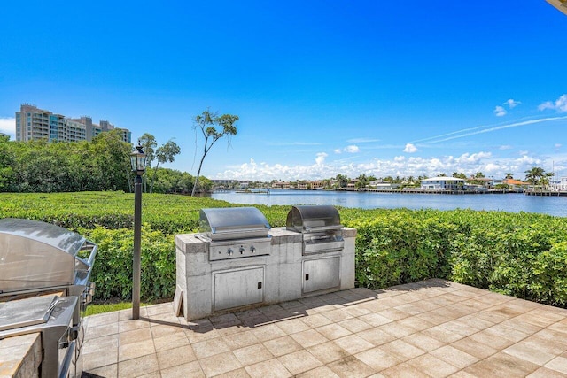 view of patio / terrace featuring an outdoor kitchen, a water view, and area for grilling