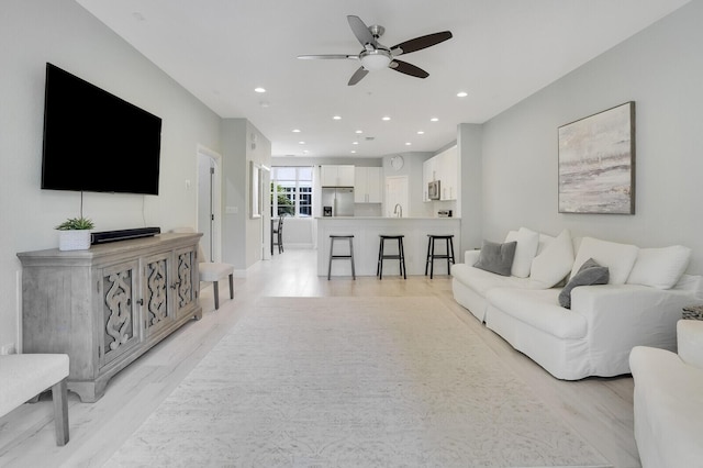 living room with light wood-type flooring and ceiling fan