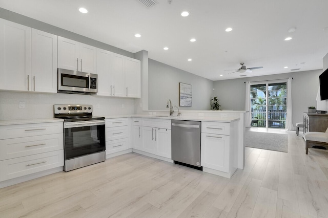 kitchen featuring kitchen peninsula, sink, ceiling fan, appliances with stainless steel finishes, and white cabinetry