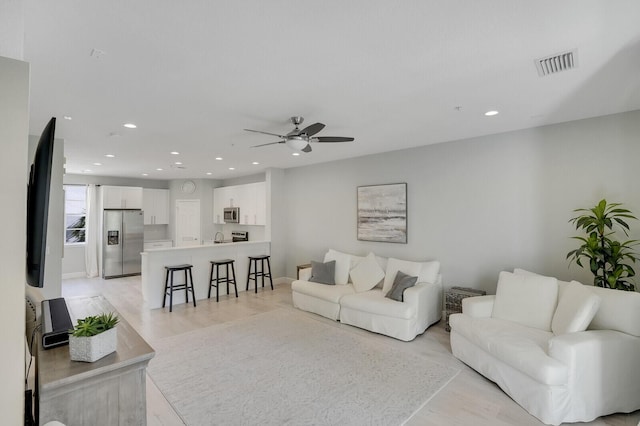 living room with ceiling fan and light wood-type flooring